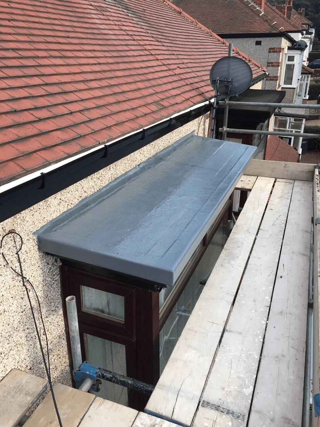 Finished flat roof installation beside a tiled roof